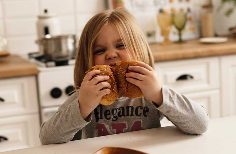 子供がパンを美味しそうに食べる画像